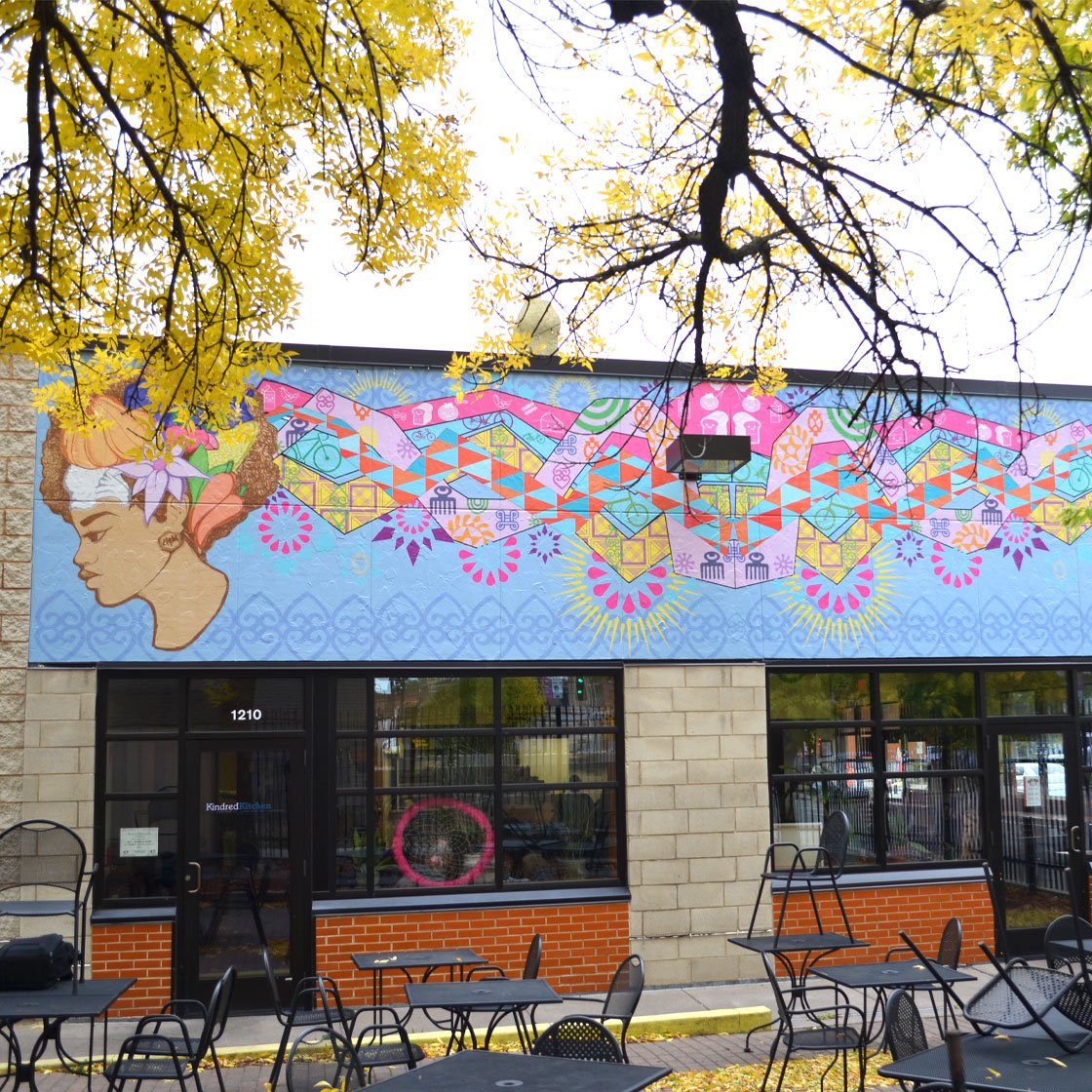 A restaurant patio decorated by a large-scale colorful mural of a woman with long flowing colorful hair