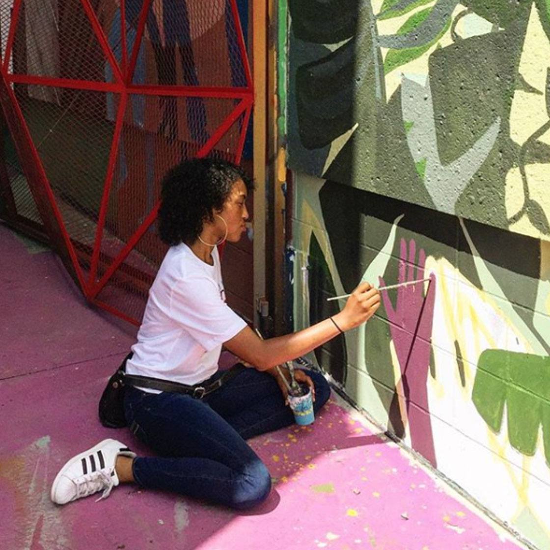 A young person painting a large-scale outdoor mural