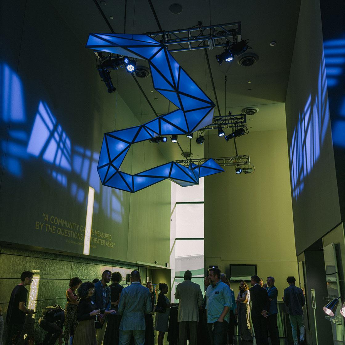 A large scale sculptural light based art installation with people standing underneath