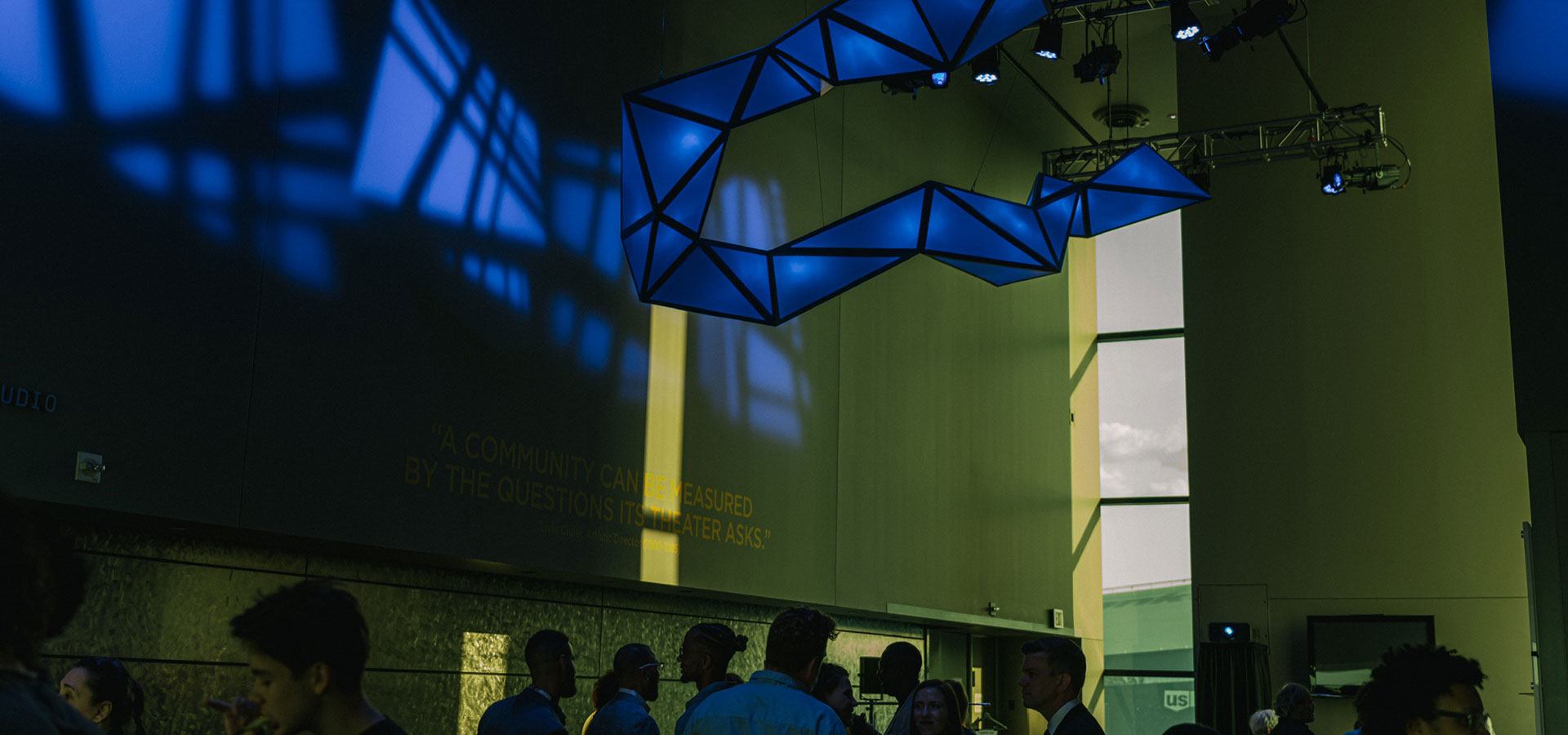 Several people milling about underneath a light-based sculpture installation