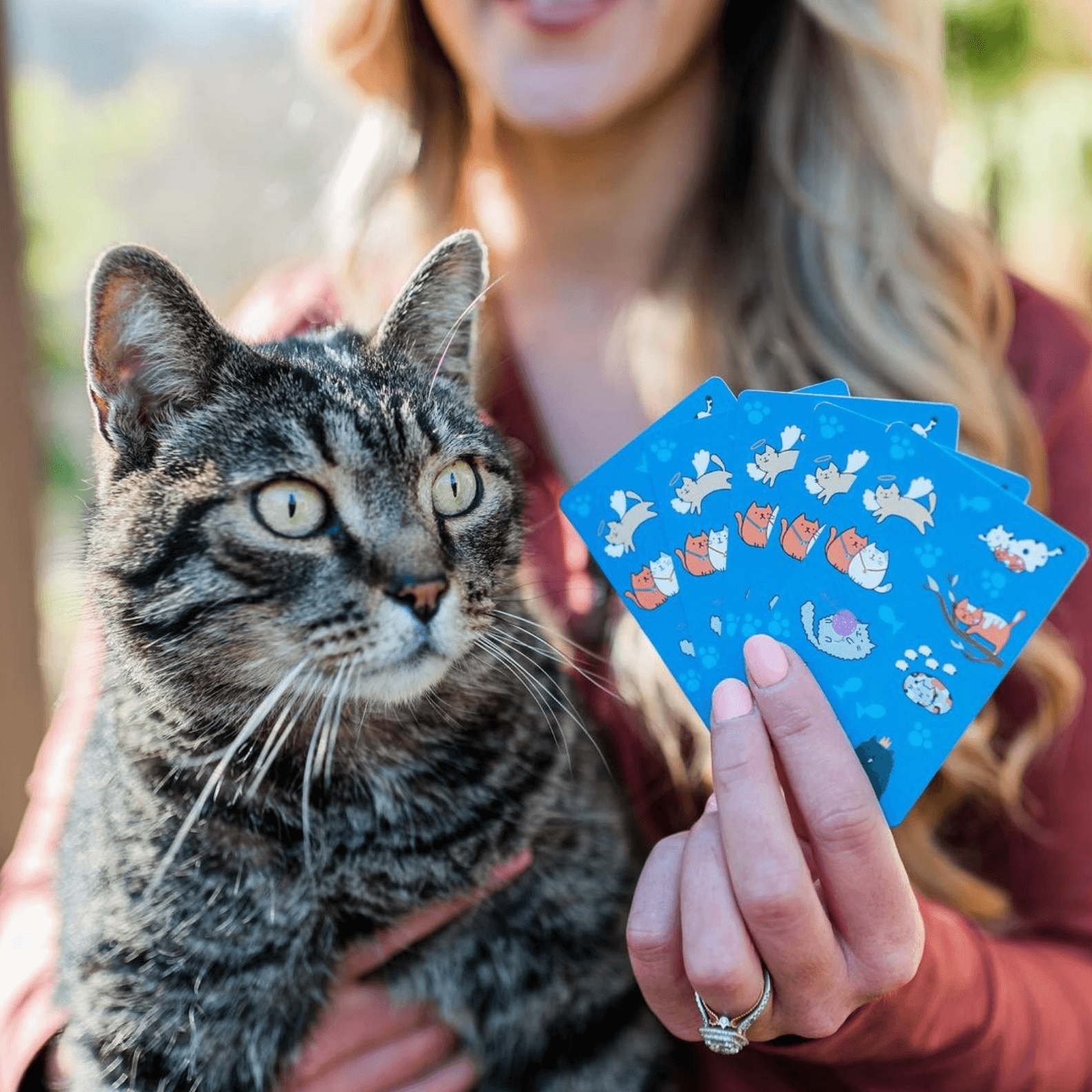 Woman holding a cat and an illustrative deck of cards.