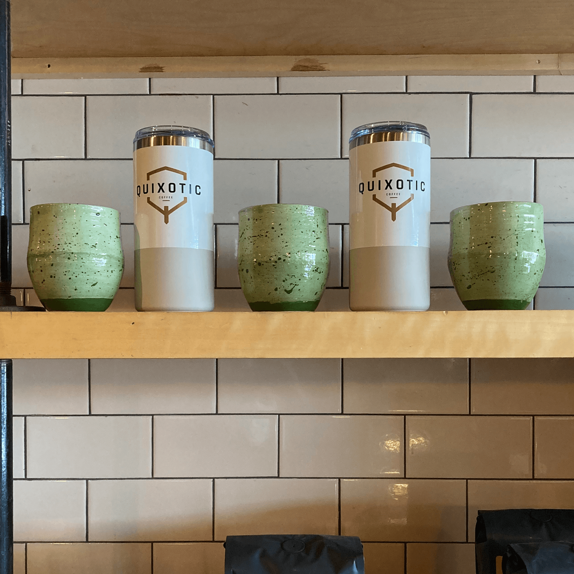 Display shelf with green ceramic mugs and coffee tumblers